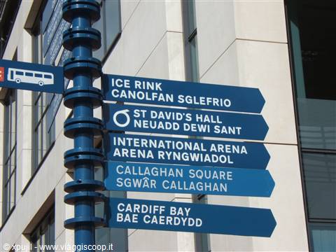 Blue signpost with bilingual directional signs at Cardiff Bay