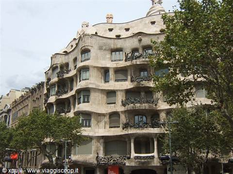 Gaudí's La Pedrera in Barcelona, wavy stone facade among the trees