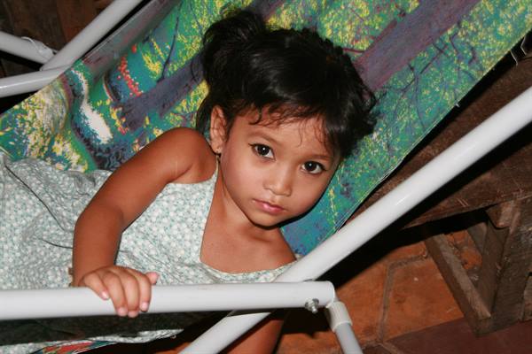 Little girl lying on a folding lounge chair, looking at the camera