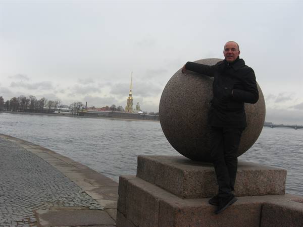 Man leaning on a granite sphere by the Neva river, Saint Petersburg