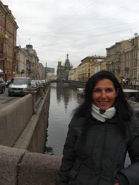 Smiling woman on bridge along canal, Church of the Savior on Spilled Blood behind, Saint Petersburg