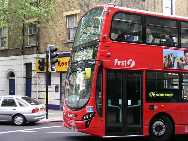 Red First double-decker bus on route 476 beside a car and traffic light