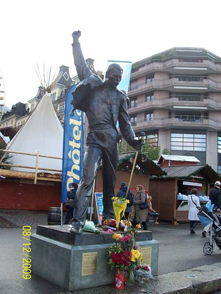 Freddie Mercury bronze statue with raised fist in Montreux, flowers at its base