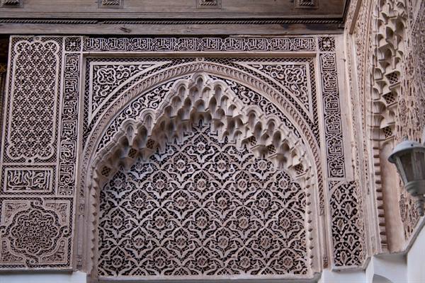 Horseshoe arch with carved stucco and Arabic calligraphy in soft light