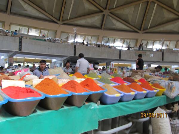 Spice sellers with colorful bowls under the dome of Chorsu Bazaar in Tashkent