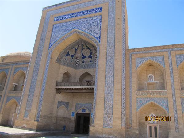 Brick madrasa with arched portal decorated with blue majolica tiles in Khiva