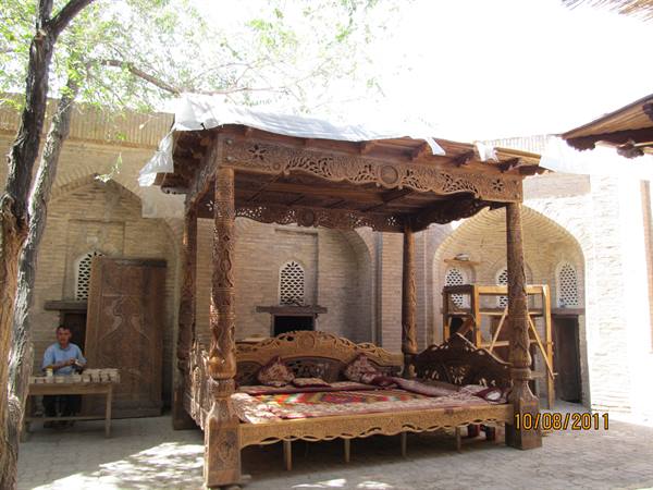 Courtyard with carved wooden canopied daybed among brick arches and lattice windows