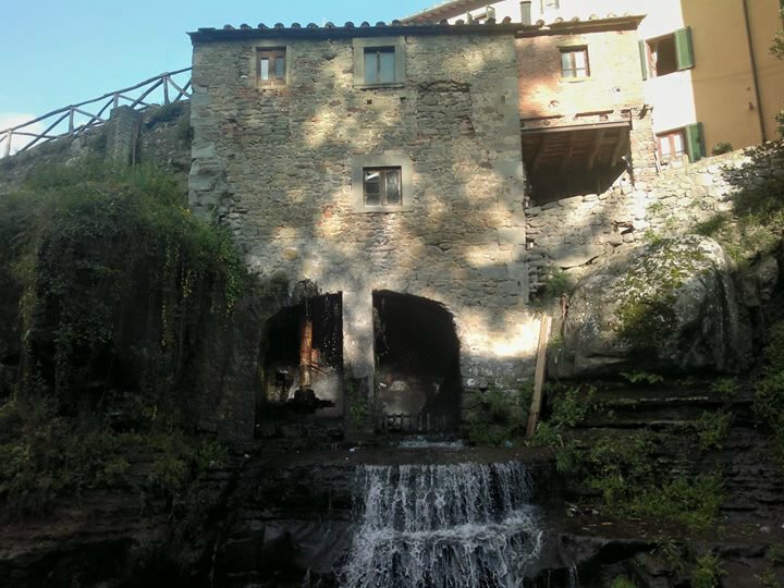 Antico mulino in pietra con arcate sopra una cascata