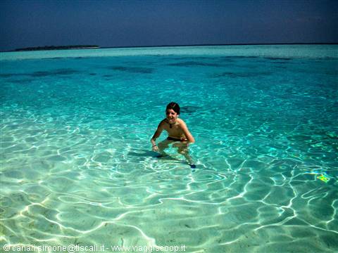 Child wading in clear turquoise water, island visible in the distance