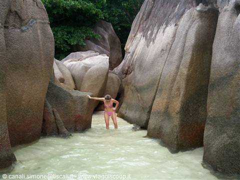 Woman in bikini wading between giant granite boulders, Anse Source d'Argent
