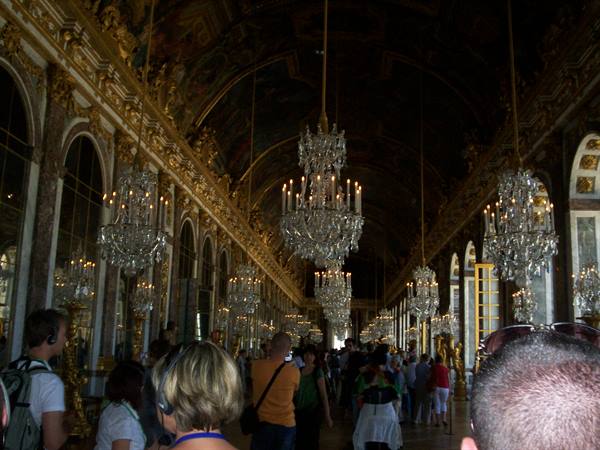 Hall of Mirrors at Versailles, lit crystal chandeliers among tourists