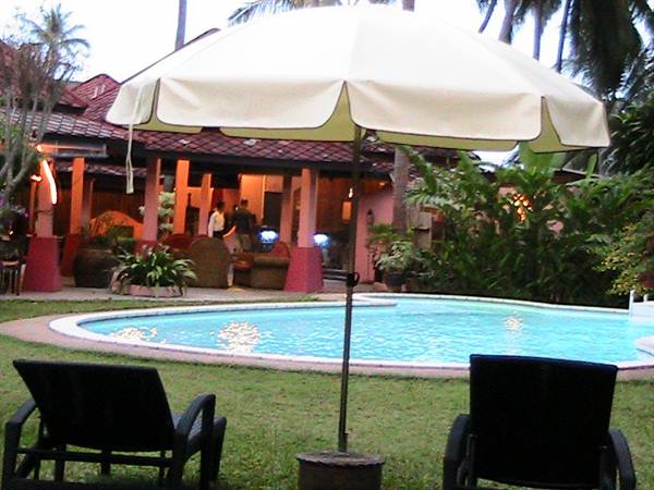 White umbrella over black lounge chairs beside the hotel pool