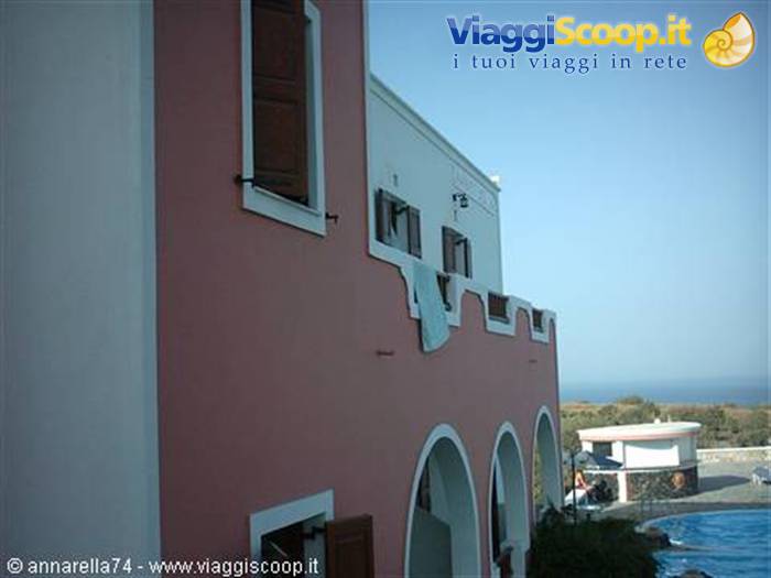 Pink and white hotel arches with pool, sea in the background