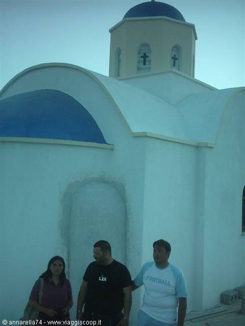 Tourists in front of white church with blue domes in Santorini