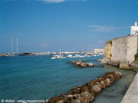Harbor with boats and old stone walls beside the turquoise sea