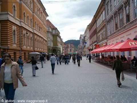 Busy pedestrian street with colorful buildings and red umbrellas, Brasov