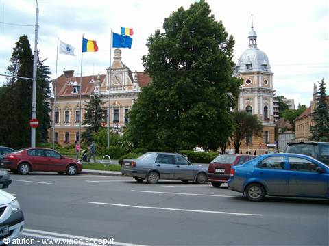 Cars passing by historic buildings with flags in Sibiu