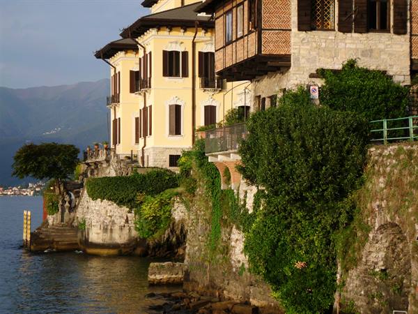 Historic villas overhanging the water at Orta San Giulio, stone walls and golden light