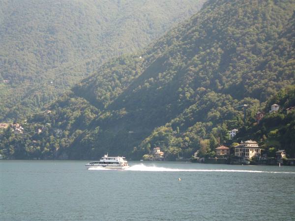Fast ferry crossing the green waters of Lake Como among wooded hills