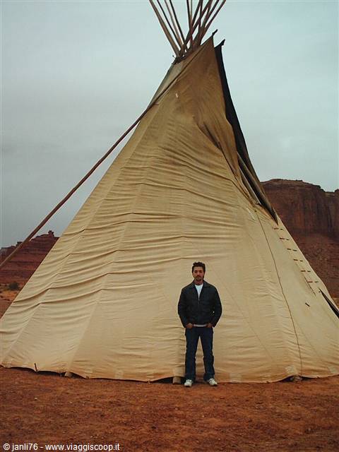 Man standing in front of a canvas tipi in Monument Valley's red desert