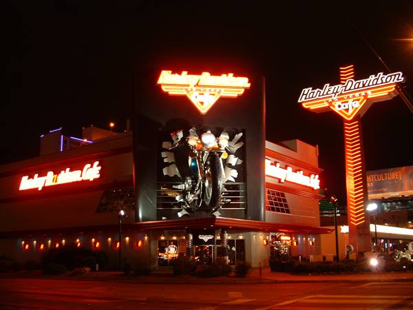 Harley-Davidson Cafe at night, giant illuminated motorcycle bursting through the facade
