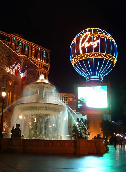 Illuminated fountain at night beneath the Paris hotel's neon hot-air balloon sign