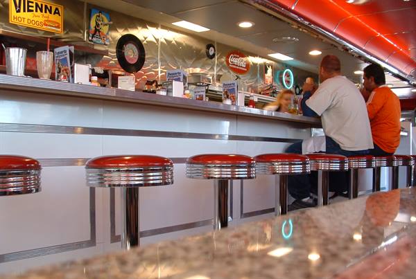 Customer at the counter of an American diner with red chrome stools