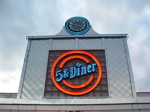Orange and blue neon signs of 5 & Diner on a chrome facade