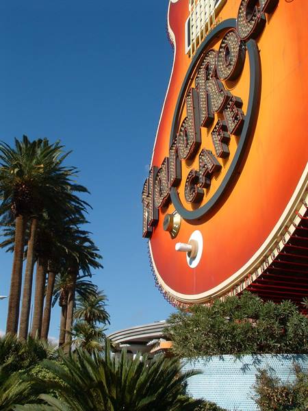 Hard Rock Cafe guitar-shaped sign among palm trees under blue sky