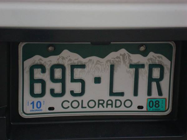 Green and white license plate 695-LTR on a car, Colorado with mountains