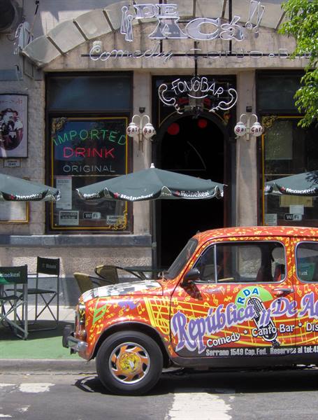 Colorful painted car outside the De Acá comedy café bar, Heineken umbrellas