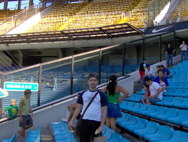 Tourist among the blue seats of Maracanã stadium, yellow stands and glass barriers