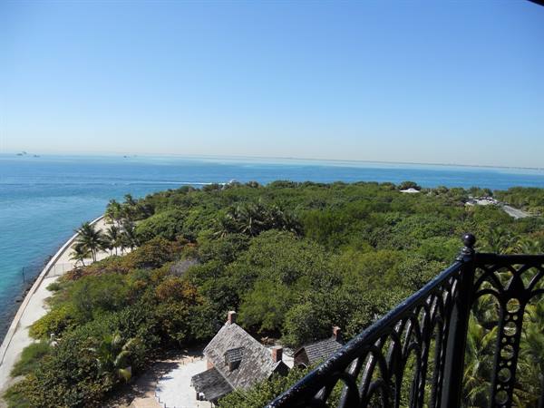 From Cape Florida Lighthouse terrace, iron railing, rooftops and tropical greenery by the ocean