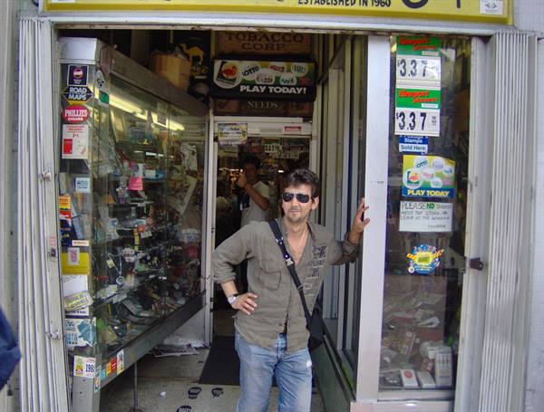 Man with sunglasses standing at the entrance of a tobacco and lottery shop