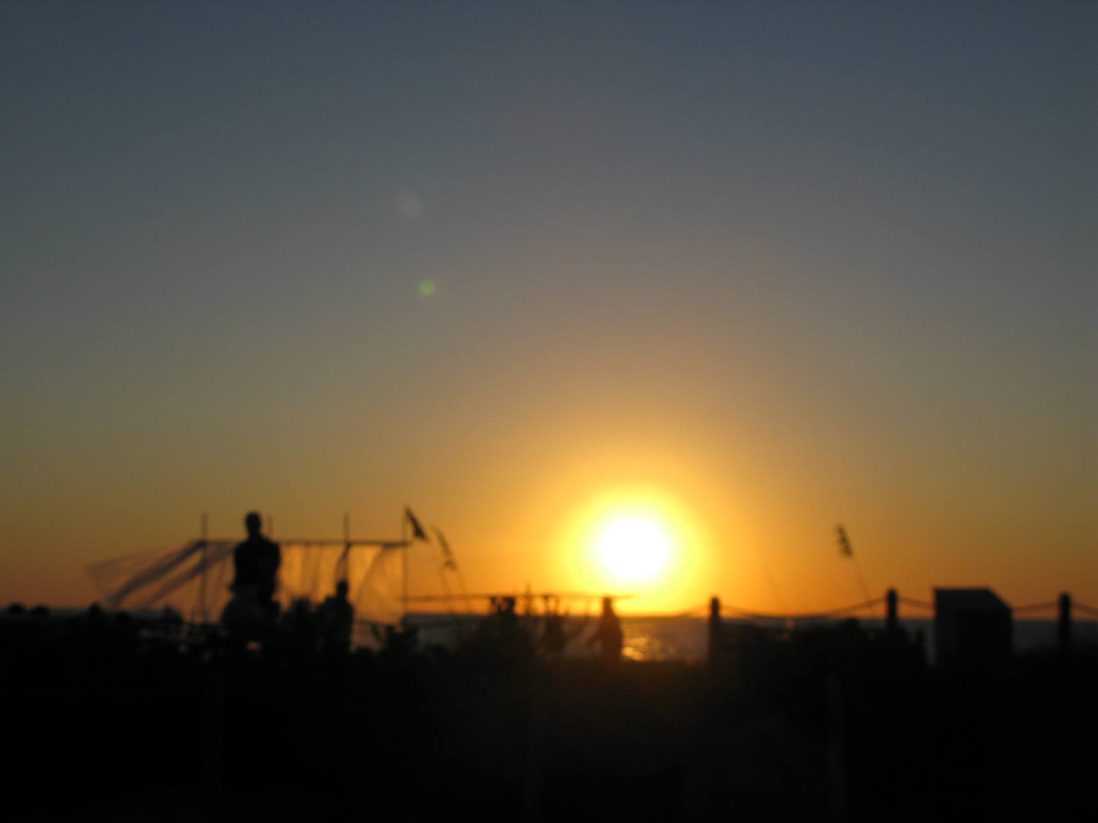 Fishermen silhouettes with nets on the pier, sun setting over the sea