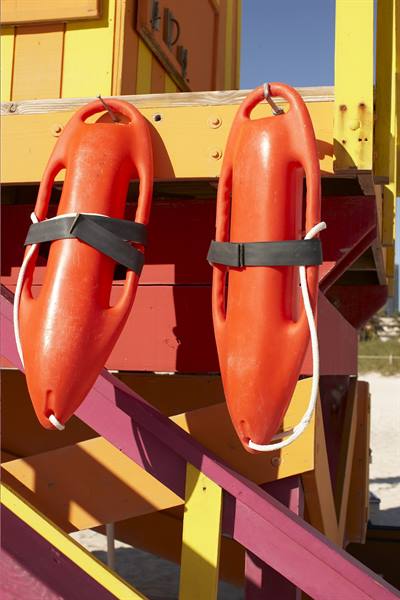 Two orange rescue cans hanging on a colorful lifeguard tower
