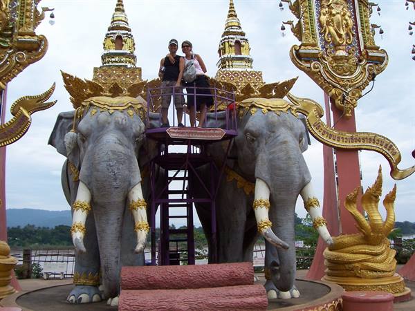 Tourists on platform between gold-decorated elephant statues and naga, Chiang Saen