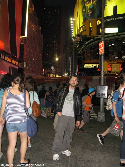 Tourist in leather jacket among the night crowd under Times Square glowing billboards