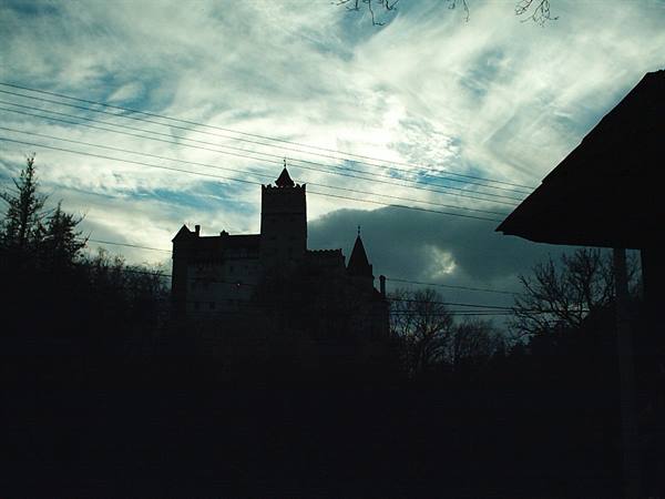 Bran Castle silhouetted against dramatic clouds and power lines
