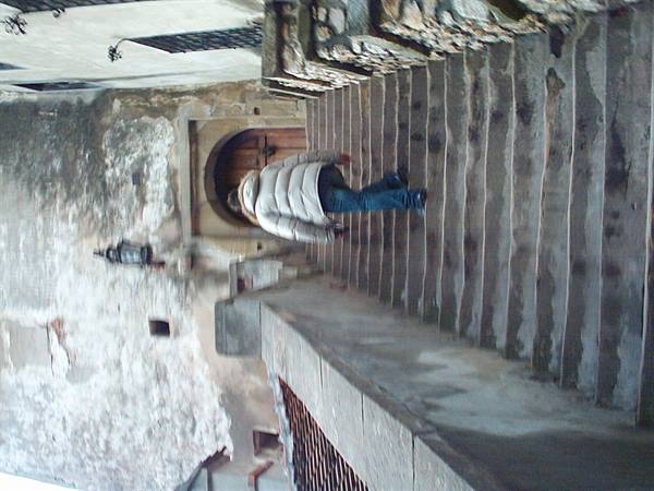 Person in puffer jacket descending a stone staircase toward an old wooden door