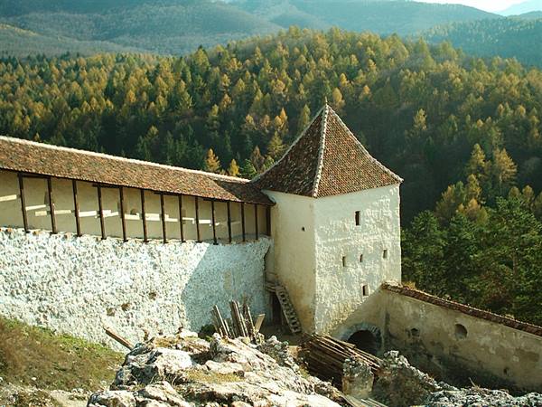 White tower and fortified walls of Rasnov above autumn forests