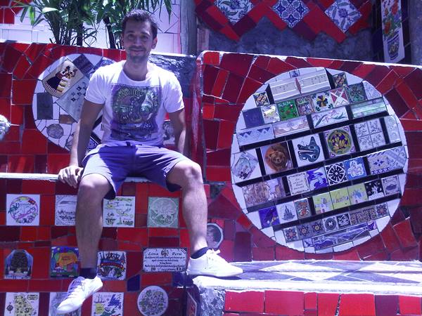 Tourist sitting on Selarón's red tiled steps, colorful mosaic circles