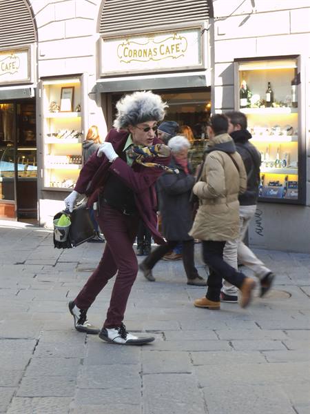 Man in grey wig and burgundy suit walks past Coronas Cafe