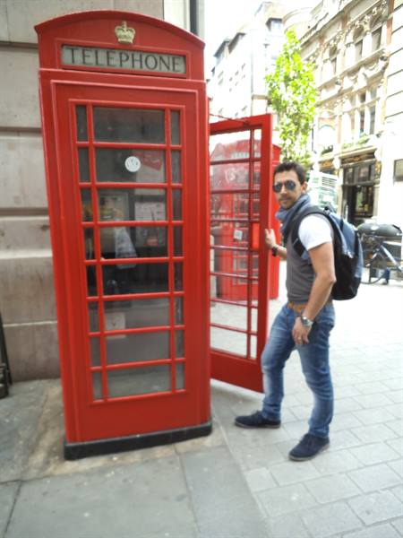 Tourist with backpack steps out of a red telephone booth in London