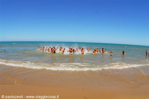 Group of tourists playing in a circle in the turquoise sea by the beach