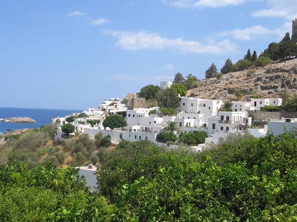 Whitewashed houses of Lindos on a green hill above the sea