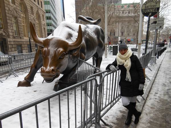 Smiling woman next to the snow-covered Charging Bull statue in Wall Street