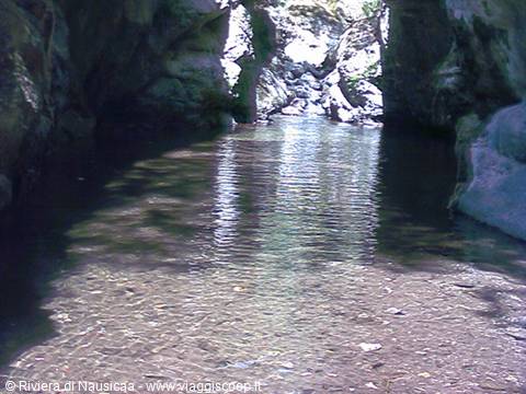Clear stream flowing between rocks and a shady cave, Rivera di Nausicaa