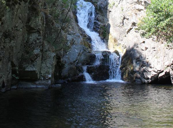 Waterfall cascading over gray rocks into a dark pool
