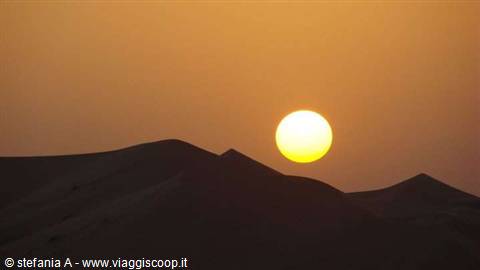 Low sun over dark sand dunes in the desert